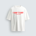 Front view of an oversized white heavyweight cotton t-shirt with bold red text reading 'I CAN'T FLIRT' and 'I'M AFRAID OF WOMEN' in a minimalist cafe setting. Part of the Unhinged Brats ironic streetwear collection.