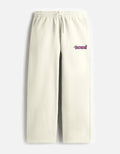 A front view of cream-colored, loose-fit terry fabric sweatpants featuring a drawstring elastic waistband and a small pink Kuromi graphic on the left thigh.