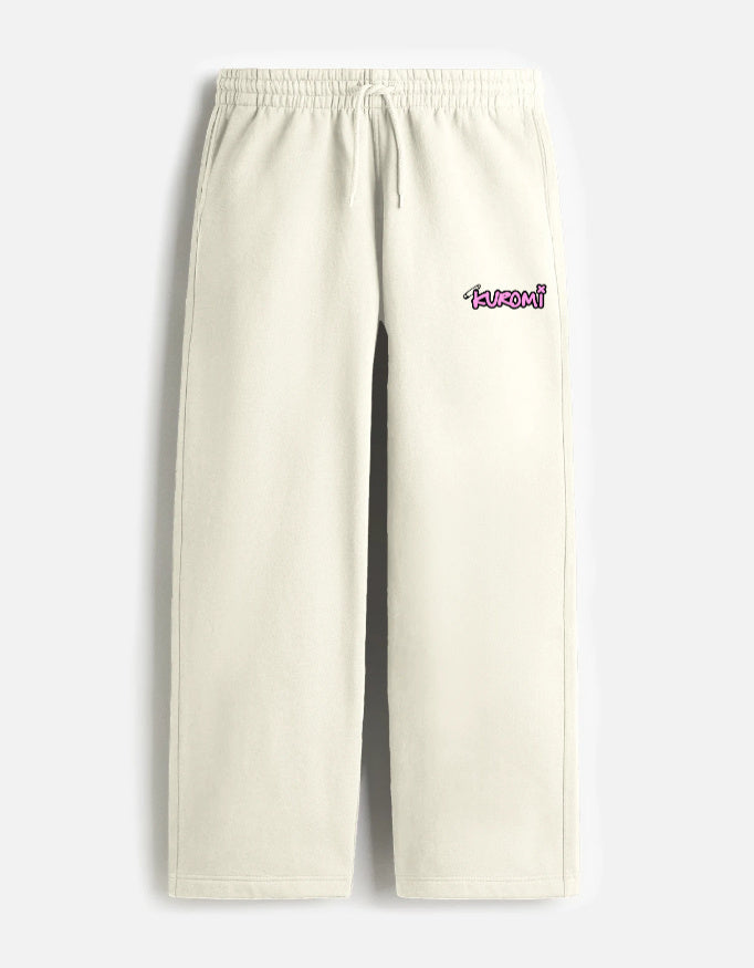 A front view of cream-colored, loose-fit terry fabric sweatpants featuring a drawstring elastic waistband and a small pink Kuromi graphic on the left thigh.