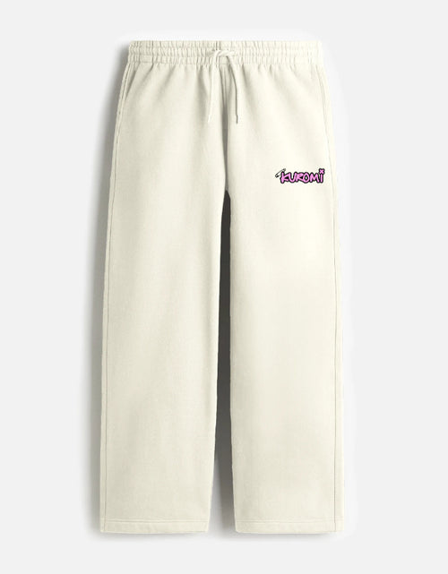 A front view of cream-colored, loose-fit terry fabric sweatpants featuring a drawstring elastic waistband and a small pink Kuromi graphic on the left thigh.