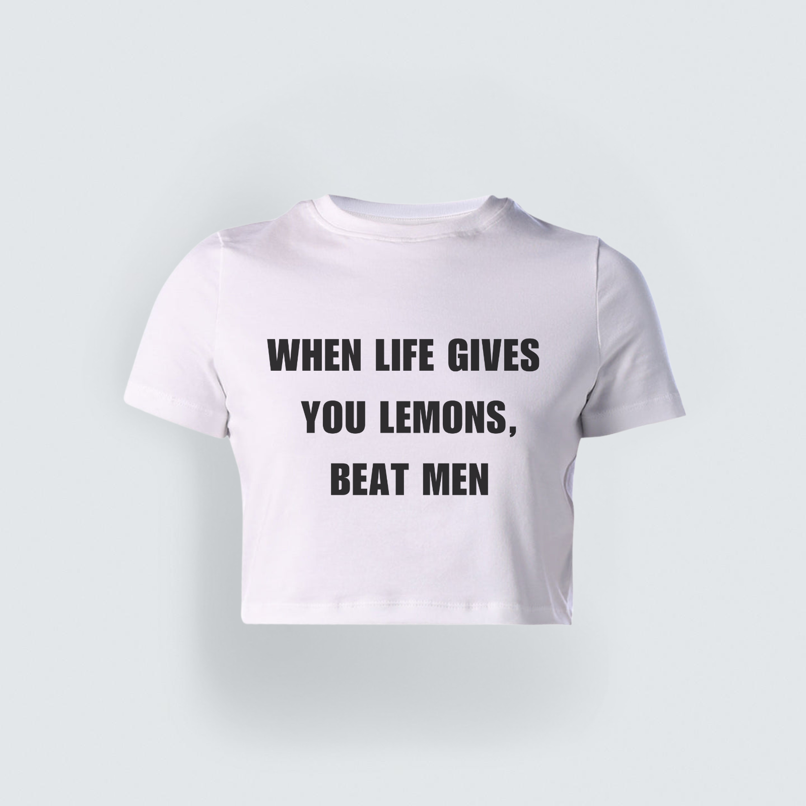 White cropped baby tee with bold black text reading "When Life Gives You Lemons, Beat Men," styled in a Gen-Z streetwear aesthetic.