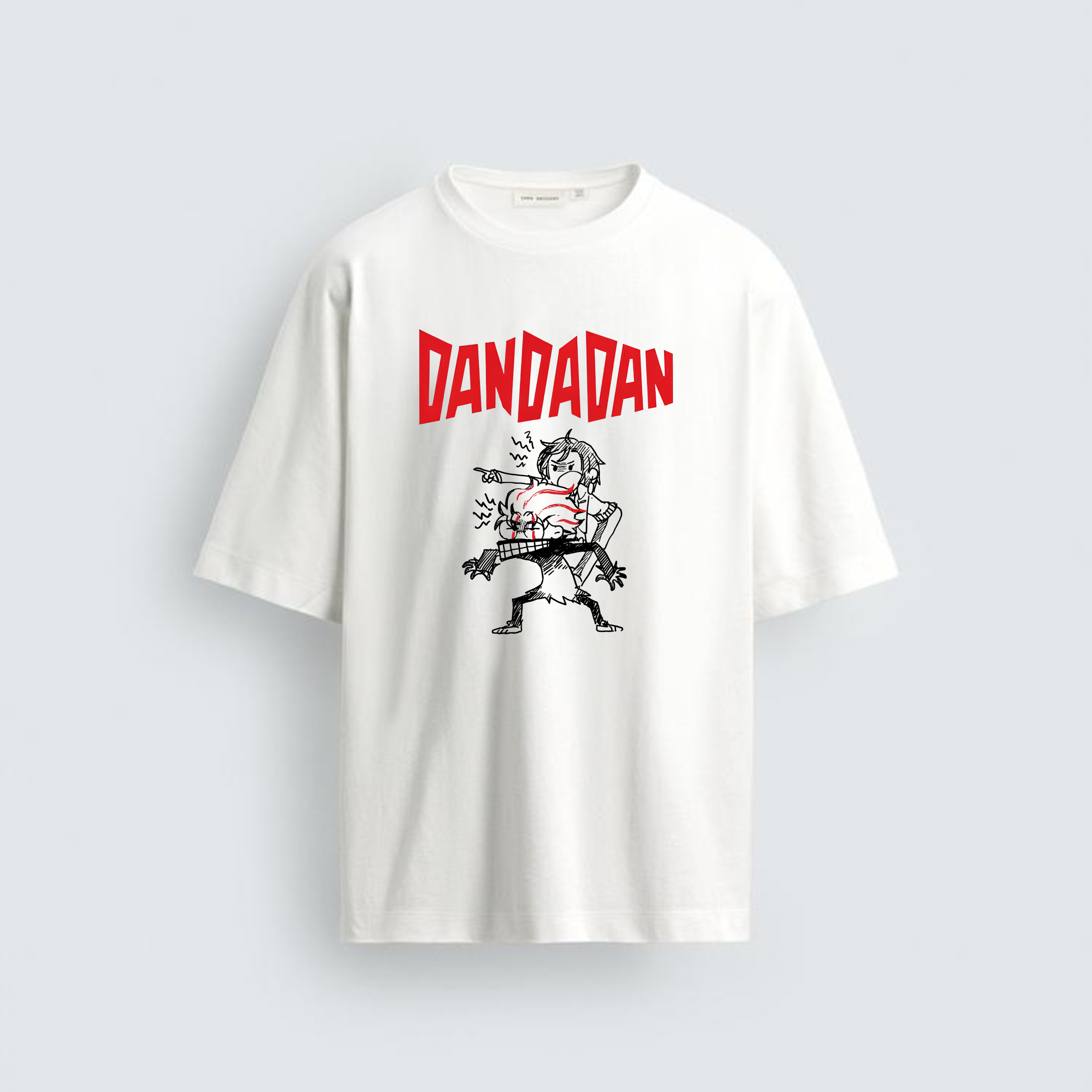 A photograph of a plain white oversized cotton tee from image_0.png. In the center, a graphic shows the jagged red text "DANDADAN" above a punk-style black and white illustration of two aggressive characters with spiky hair, dynamic and shouting.